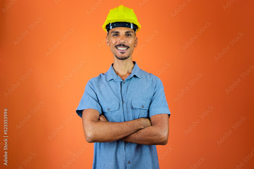 Engineers day - Black Man in Safety Helmet and Blue Shirt isolated on orange.