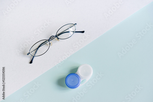 Glasses and a case for contact lenses on a white and blue background. concept of choosing a method of vision correction. copy space