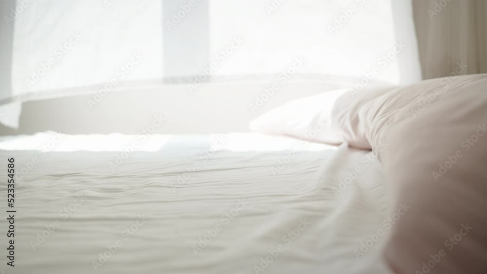 It's a sunny morning, the light from the window falls on the white bed, the wind blows the curtains. Dolly slider close-up. It's a sunny morning, the light from the window falls on the white bed, the wind blows the curtains. Dolly slider close-up.