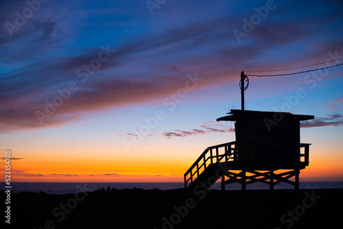 Silhouettes of lifeguard house at sunset time.