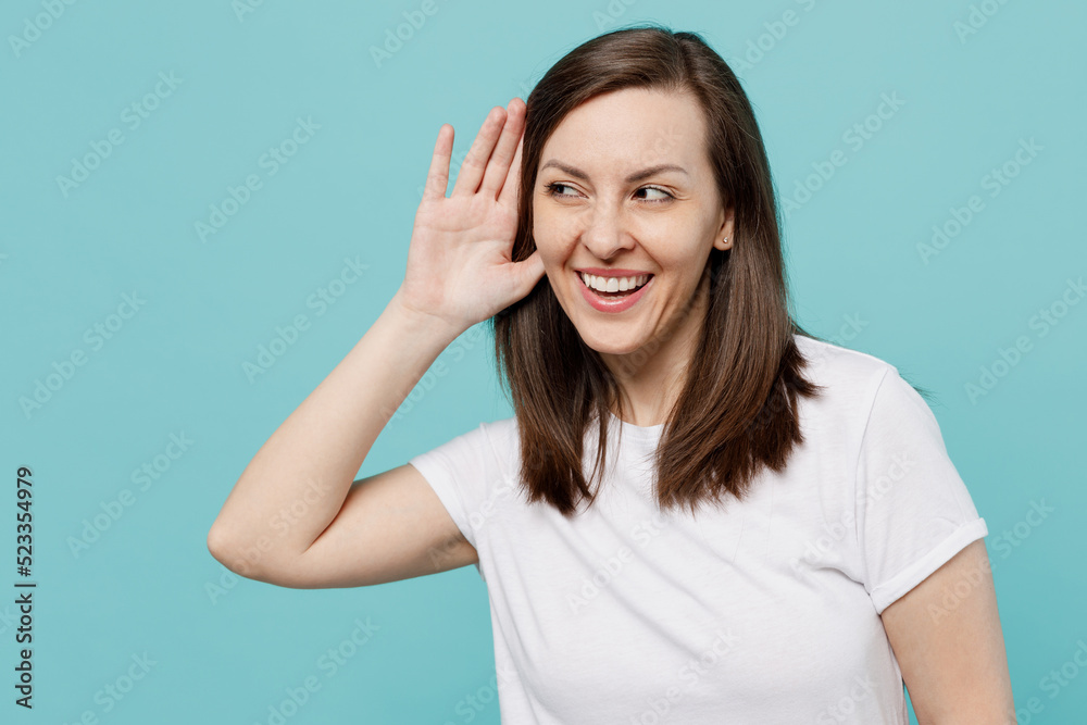 Young curious nosy caucasian woman 20s she wear white t-shirt try to hear you overhear listening intently isolated on plain pastel light blue cyan background studio portrait. People lifestyle concept. Young curious nosy caucasian woman 20s she wear white t-shirt try to hear you overhear listening intently isolated on plain pastel light blue cyan background studio portrait. People lifestyle concept.