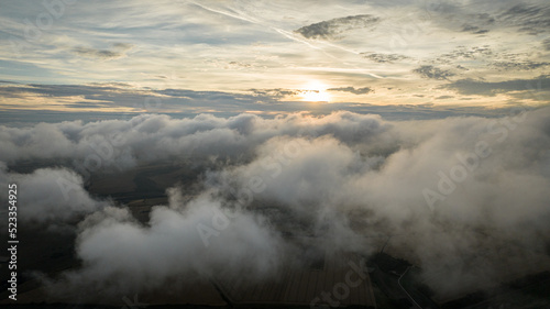 Aerial view of a cloudy sunset while flying above the clouds.