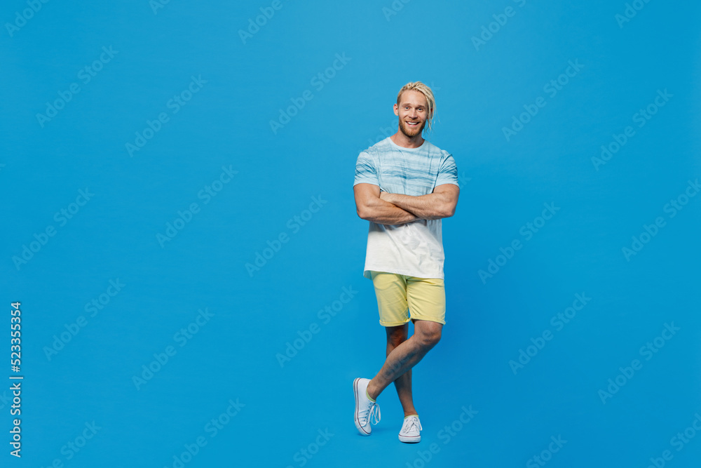 Full body young blond man with dreadlocks 20s he wear white t-shirt look camera hold hands crossed folded look camera isolated on plain pastel light blue background studio. People lifestyle concept.