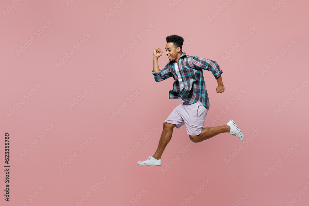 Full body side view young hurrying caucasian man of African American ethnicity 20s he wear blue shirt run fast isolated on plain pastel light pink background studio portrait. People lifestyle concept.