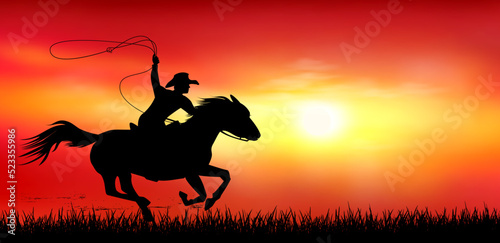 Cowboy on horseback at sunset. A man riding a horse. Cowboy with a lasso in his hands. A horse rider gallops against the backdrop of a sunset © Oleg Lytvynenko