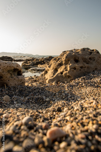 Stony beach. Pebbles on the shore, during sunset. 