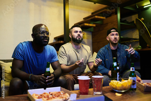 Wallpaper Mural Group of young interracial buddies watching football match broadcast in garage w