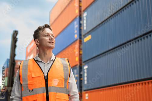 Caucasian handsome young man worker working in container port terminal. Attractive foreman worker process orders and product at warehouse logistic in cargo freight ship for import and export in harbor