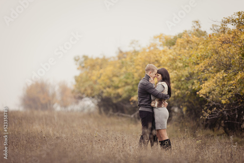 couple on autumn walk outdoors. Two lovers in autumn park. Love and tender touch. Foggy cloudy day filled with the warmth of love. Beautiful autumn landscape for couple