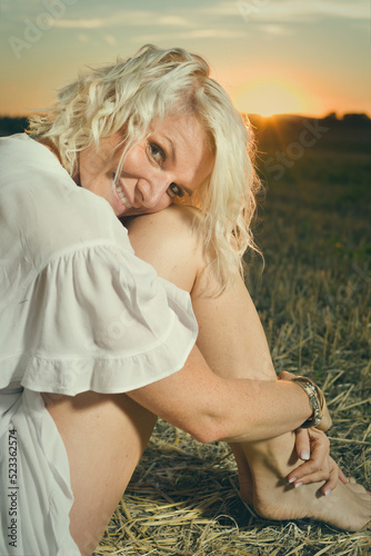 Pretty lady in summer apparel posing on harvested cornfield photo