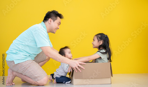 Happy african american father playing with children sitting in carton box at new home. Happy multiethinc family enjoying new home. Young parents and sons having fun during moving house. photo