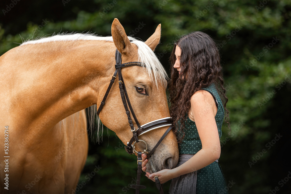 Obraz premium Equestrian and her horse team: Portrait of a young woman cuddle with her palomino kinsky warmblood horse. 