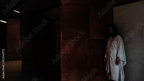 A female zombie in an abandoned house full of blood for Halloween.