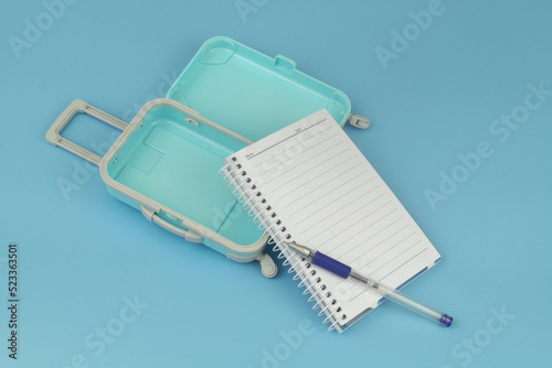 Open travel suitcase with notepad and pen. Planning travel trip concept.	