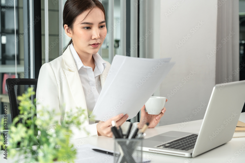Professional businesswoman analyzing graph data from document in hand, Market research reports and income statistics, Woman working in a private office, Financial and Accounting concept Professional businesswoman analyzing graph data from document in hand, Market research reports and income statistics, Woman working in a private office, Financial and Accounting concept