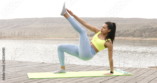 Fit woman practicing abdominal muscles workout, twisting while lying on the mat.