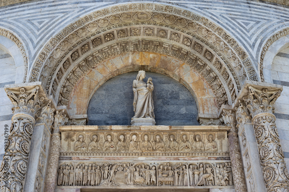 The fragment of the exterior of the Pisa Baptistery of St. John. Statue of Madonna with a child over the Baptistery portal,  the Square of Miracles (Piazza dei Miracoli) in Pisa, Italy.