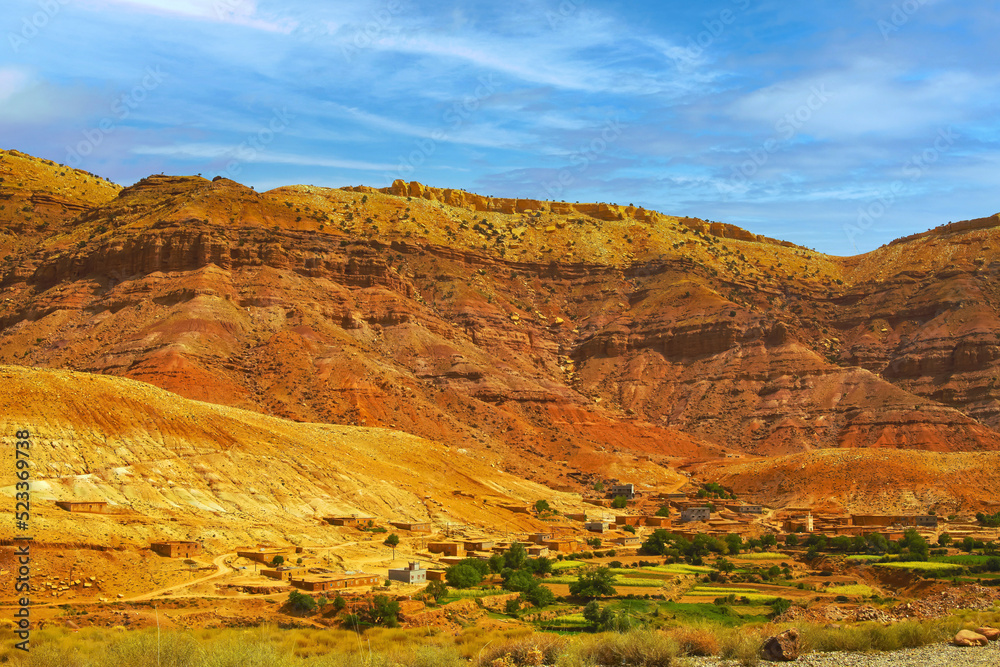 Fototapeta premium Beautiful moroccan atlas mointains valley landscape, secluded berber clay house at the foot of a steep rock face - Gorges du Dades, Morocco