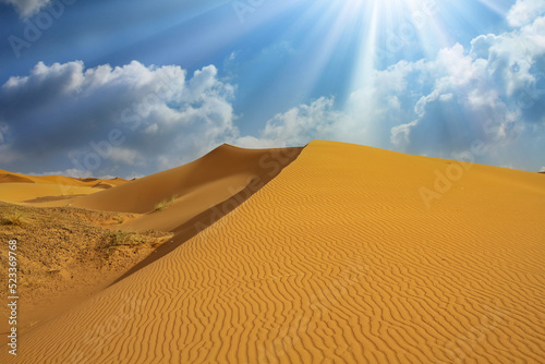 Beautiful african desert landscape, triangle shape yellow sand dune, dramatic sky clouds, sun rays backlight - Morocco, Erg Chebbi, Sahara, North Africa