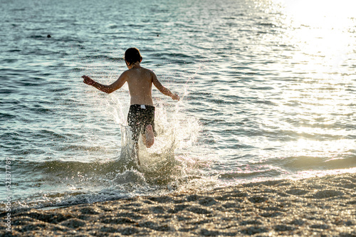 a happy boy runs into the sea and plays with the waves. Summer holidays at sea