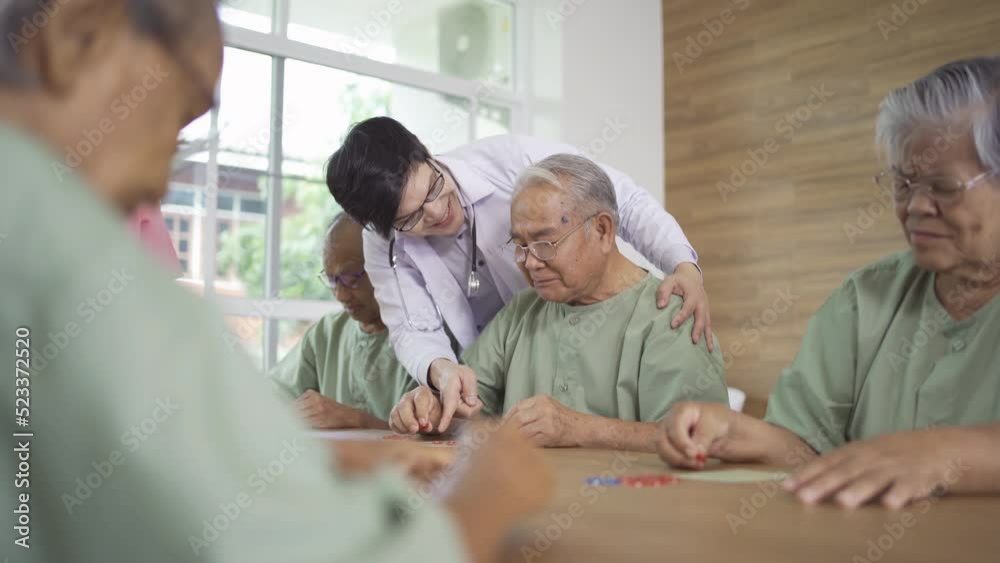 Portrait of happy group of old elderly Asian patient or pensioner people with a nurse and doctor playing games in nursing home. Senior lifestyle activity recreation. Retirement community. Health care Portrait of happy group of old elderly Asian patient or pensioner people with a nurse and doctor playing games in nursing home. Senior lifestyle activity recreation. Retirement community. Health care