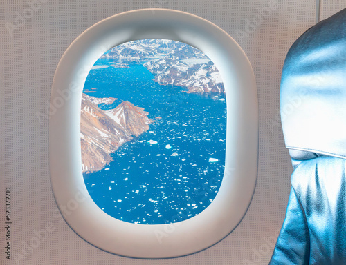 View from airplane of melting polar ice cap Greenland as seen through window of an commerical passenger airplane