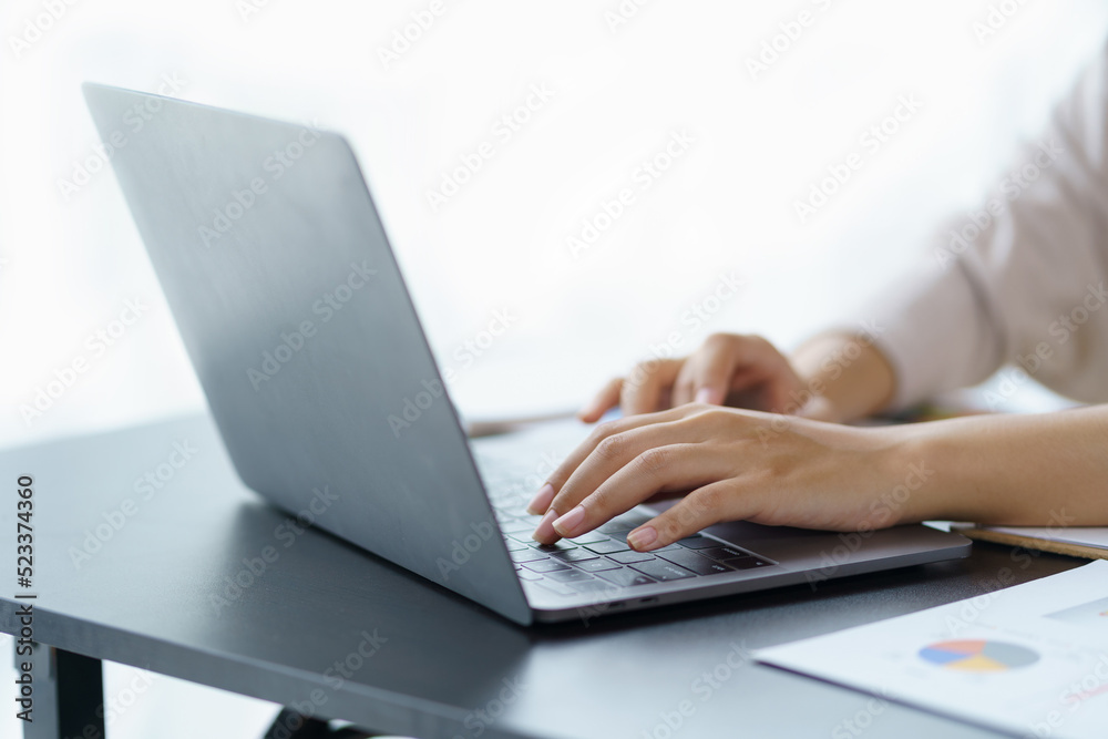 Close-up of a business woman typing a laptop computer on a desk in the office. Close-up of a business woman typing a laptop computer on a desk in the office.