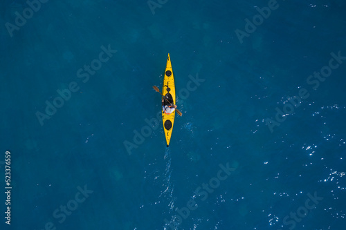 Yellow kayak In motion on blue water top view. Yellow canoe movement on water top view.