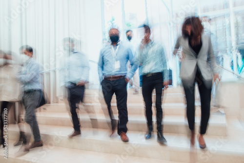 blurred businessmen and women descending the staircase