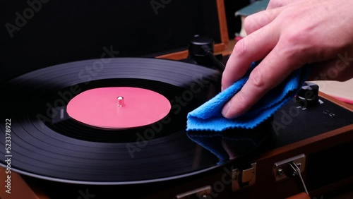 Wipe a vinyl record with a rag, dark background. Turn on the music