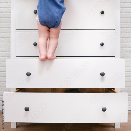 Toddler baby climbed up on the open chest of drawers Fototapet