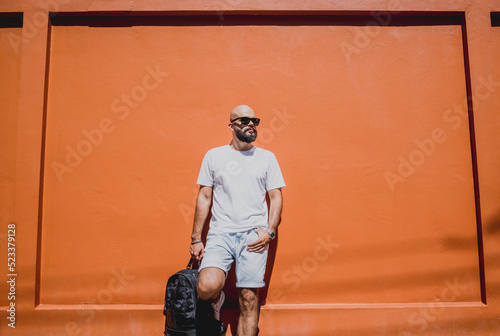 Male model with beard wearing white blank t-shirt on the background of an orange wall © romaset
