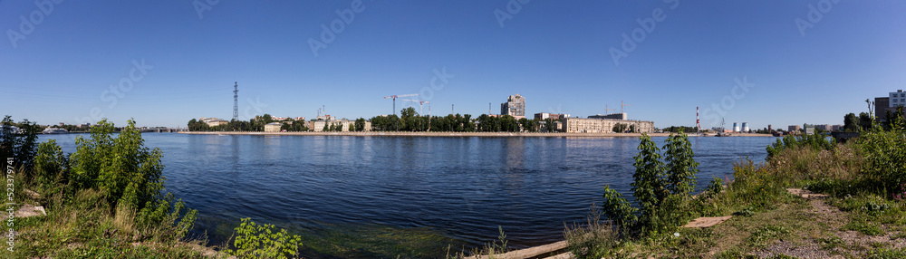 Panoramic view of the embankment of the Neva River in St. Petersburg in the Nevsky district near the river station with a view of the pipes of the thermal power plant and building cranes.