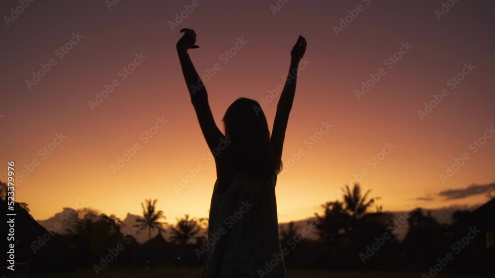 Silhouette of happy girl with her hands raised against the background of a colorful sunset sky Silhouette of happy girl with her hands raised against the background of a colorful sunset sky