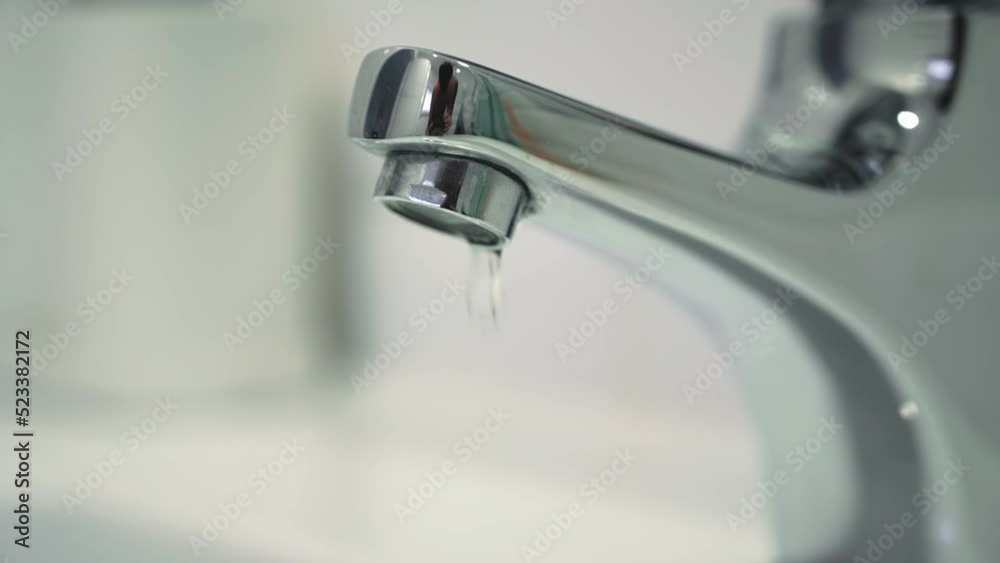 Water leak concept. Close up of water drops.Video of a faucet in a bathroom with dripping water. Faucet malfunction, drops of clean water dripping into the white washbasin Water leak concept. Close up of water drops.Video of a faucet in a bathroom with dripping water. Faucet malfunction, drops of clean water dripping into the white washbasin
