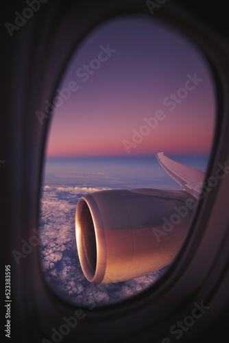 View from window of airplane during night flight above ocean. Selective focus on jet engine..