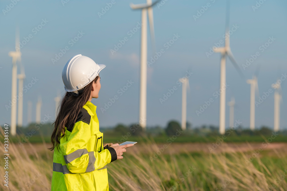women engineer working and holding the report at wind turbine farm Power Generator Station on mountain,Thailand people women engineer working and holding the report at wind turbine farm Power Generator Station on mountain,Thailand people