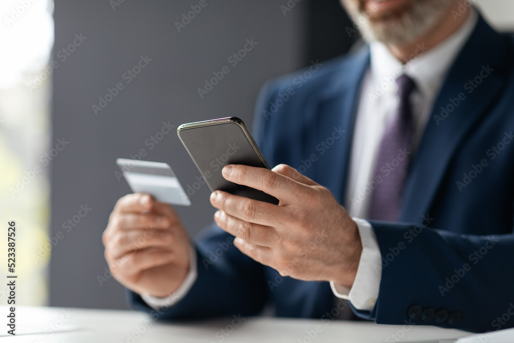 Unrecognizable Businessman Making Online Payments With Credit Card And Smartphone In Office Unrecognizable Businessman Making Online Payments With Credit Card And Smartphone In Office
