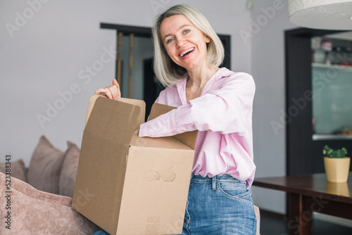 woman sitting on couch at home opening carton box received parcel package © Tatyana Gladskih