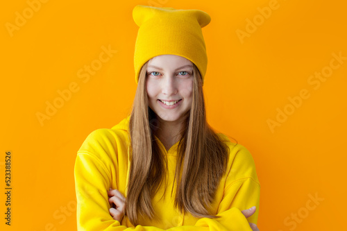Young teen girl wearing yellow hoodie and hat, Hipster