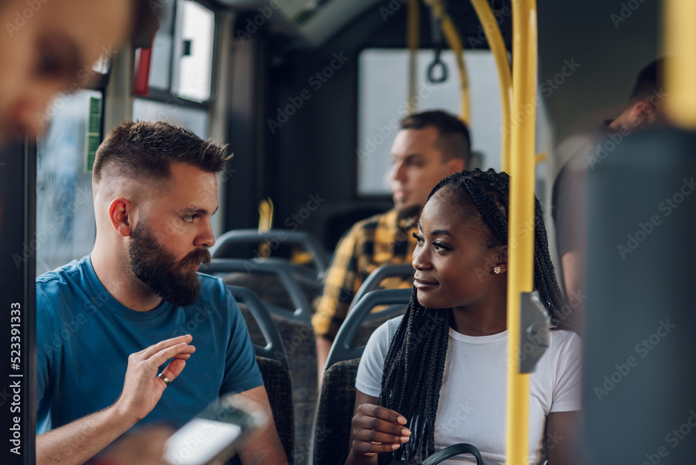Multiracial friends talking while riding a bus in the city Multiracial friends talking while riding a bus in the city