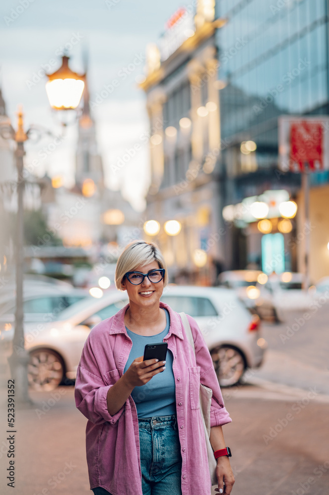 Young plus size woman using smartphone while walking in the city. Young plus size woman using smartphone while walking in the city.