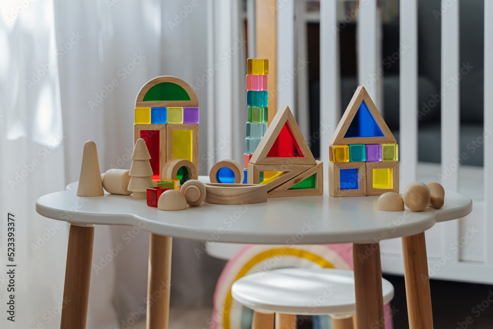 Playroom with toys. Wooden rainbow stacking blocks on the table in the kids room. Educational game for baby and toddler in modern nursery. Early development.
