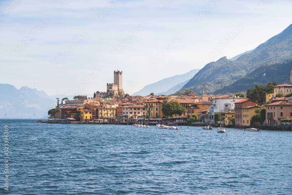 Idyllic coastline scenery in Italy, captured from the water. Blue water and a cute village at lago di garda, Malcesine Idyllic coastline scenery in Italy, captured from the water. Blue water and a cute village at lago di garda, Malcesine