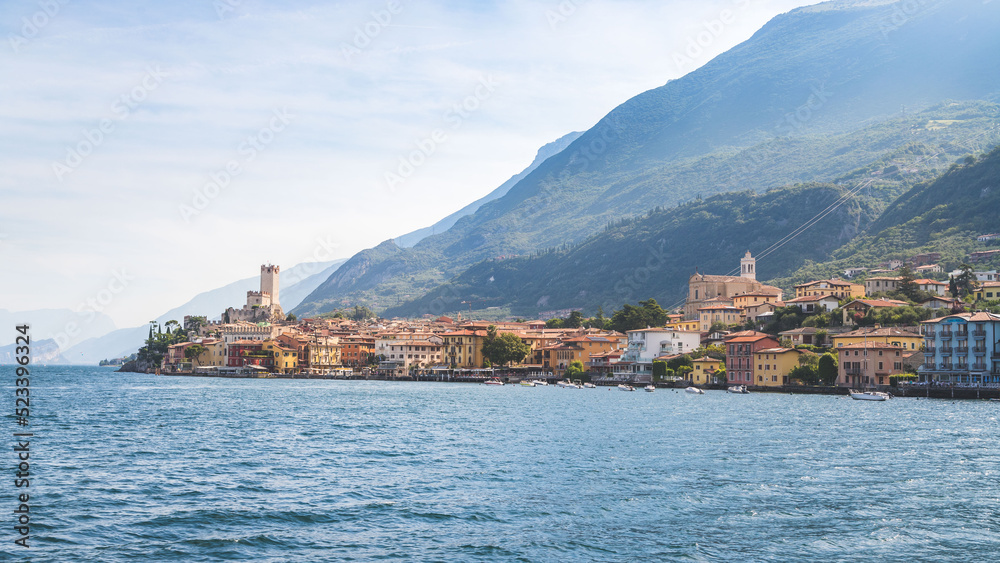 Idyllic coastline scenery in Italy, captured from the water. Blue water and a cute village at lago di garda, Malcesine Idyllic coastline scenery in Italy, captured from the water. Blue water and a cute village at lago di garda, Malcesine
