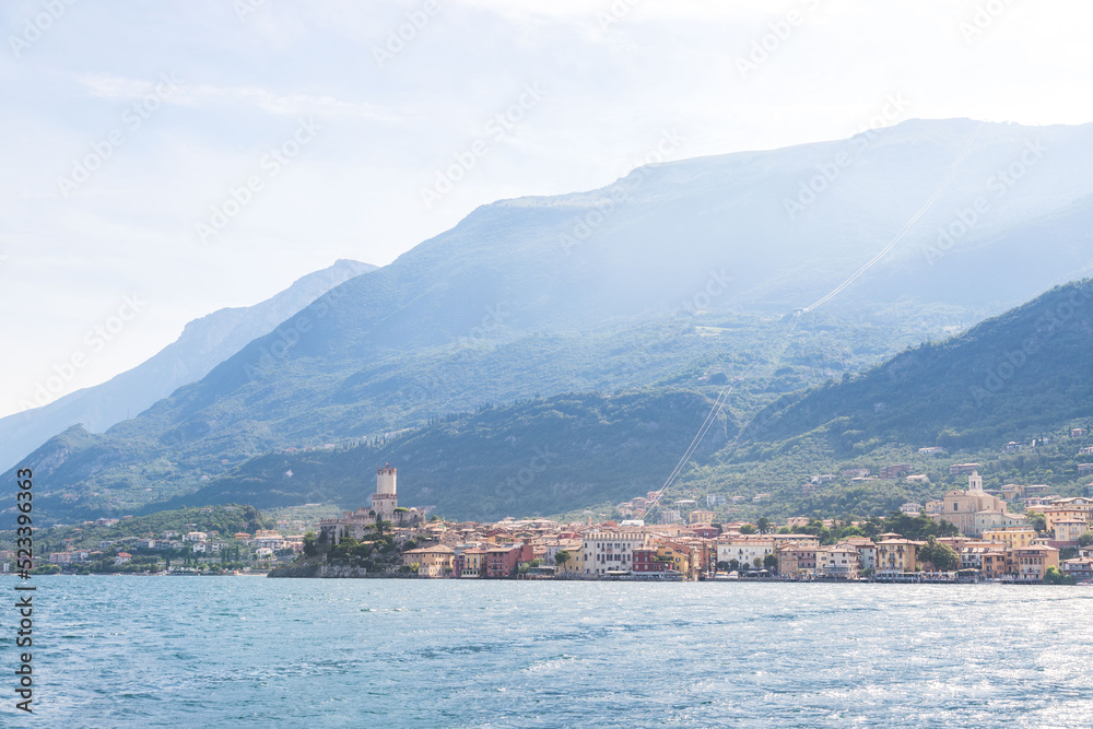 Idyllic coastline scenery in Italy, captured from the water. Blue water and a cute village at lago di garda, Malcesine