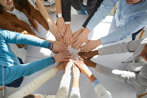 High angle view of cropped business people executive staff putting palms together, at office. Diverse men and women in formal clothes engaged in collaboration, successful cooperation