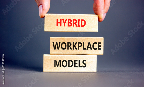 Hybrid workplace models symbol. Concept words Hybrid workplace models on wooden blocks. Businessman hand. Beautiful grey background. Business hybrid workplace models quote concept. Copy space photo