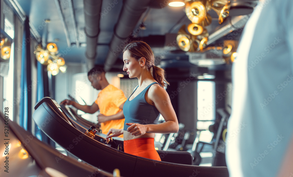 Men and woman, diversity group, in the gym exercising by running on treadmill
