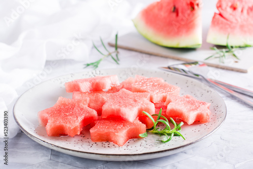 Pieces of fresh watermelon in the form of stars on a plate on the table. Summer refreshment.